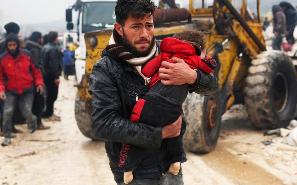 A man carries the body of an earthquake victim in the Besnia village near the Turkish border, Idlib province - AP