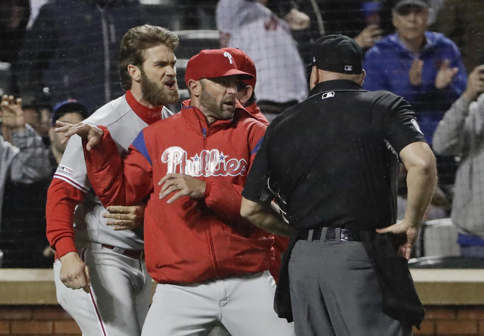 Philadelphia Phillies manager Gabe Kapler, center, restrains Bryce Harper, left, while arguing a call with umpire Mark Carlson during the fourth inning of a baseball game Monday, April 22, 2019, in New York. (AP Photo/Frank Franklin II)