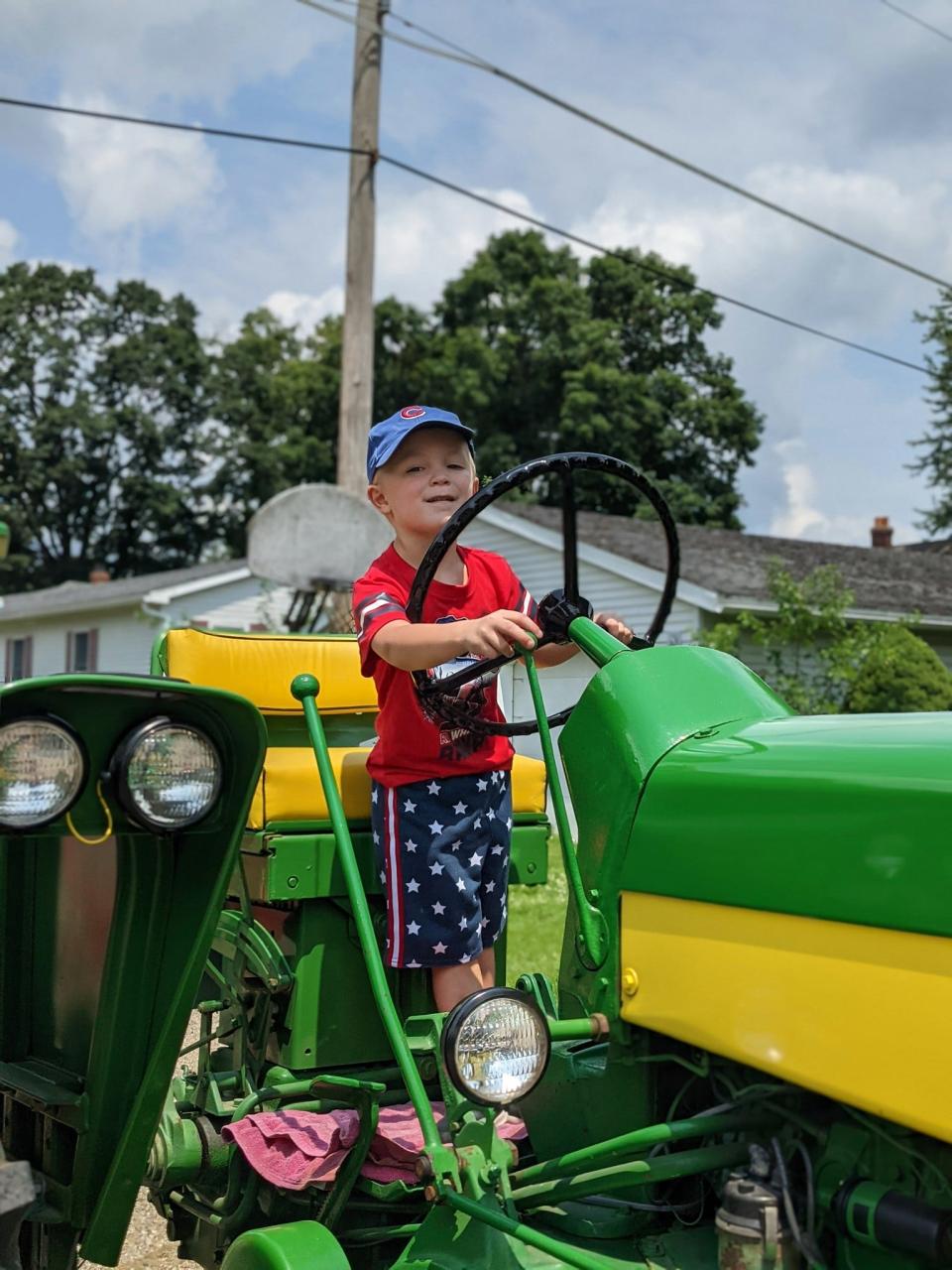 Prior to the Emden parade starting Tate Sheley, son of Chris and Andrea Sheley, enjoys playing on the tractor.