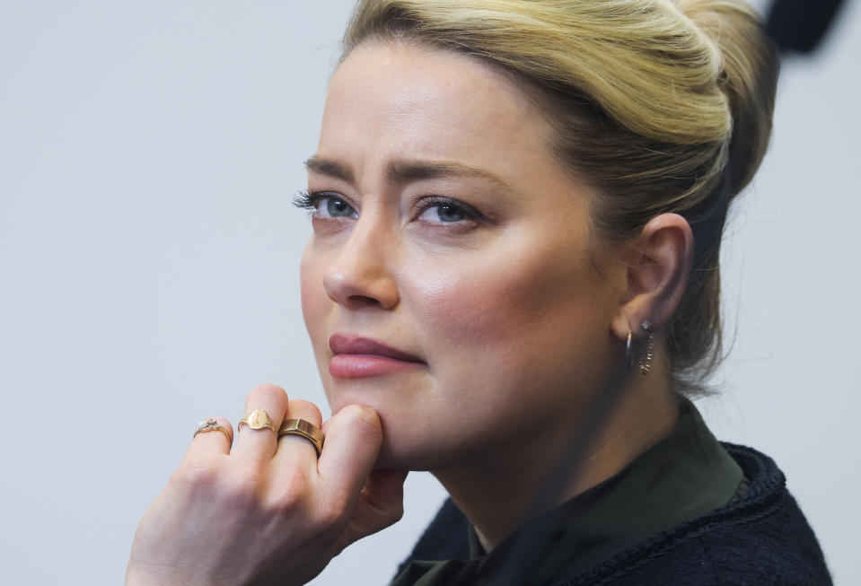 Actor Amber Heard listens to her ex-husband actor Johnny Depp's testimony in the courtroom in the Fairfax County Circuit Courthouse in Fairfax, Va., Wednesday, May 25, 2022. Depp sued Heard for libel in Fairfax County Circuit Court after she wrote an op-ed piece in The Washington Post in 2018 referring to herself as a "public figure representing domestic abuse." (Evelyn Hockstein/Pool photo via AP)