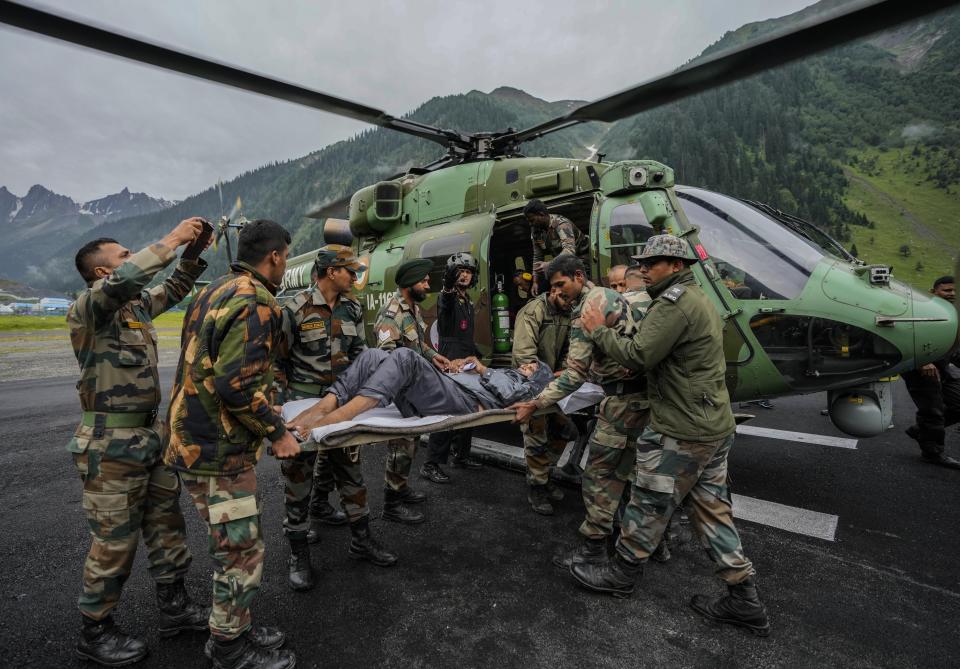 Indian army soldiers carry an injured of a cloudburst for treatment, at Baltal, 105 kilometers (65miles) northeast of Srinagar, Indian controlled Kashmir, Saturday, July 9, 2022. At least eight pilgrims have been killed after a cloudburst triggered a flash flooding during an annual Hindu pilgrimage to an icy Himalayan cave in Indian-controlled Kashmir. Officials say the cloudburst near the hollowed mountain cave revered by Hindus on Friday sent a wall of water down a mountain gorge and swept about two dozen encampments and two makeshift kitchens. (AP Photo/Mukhtar Khan)