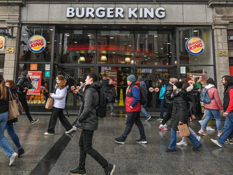 People with coats walking past a Burger King restaurant.