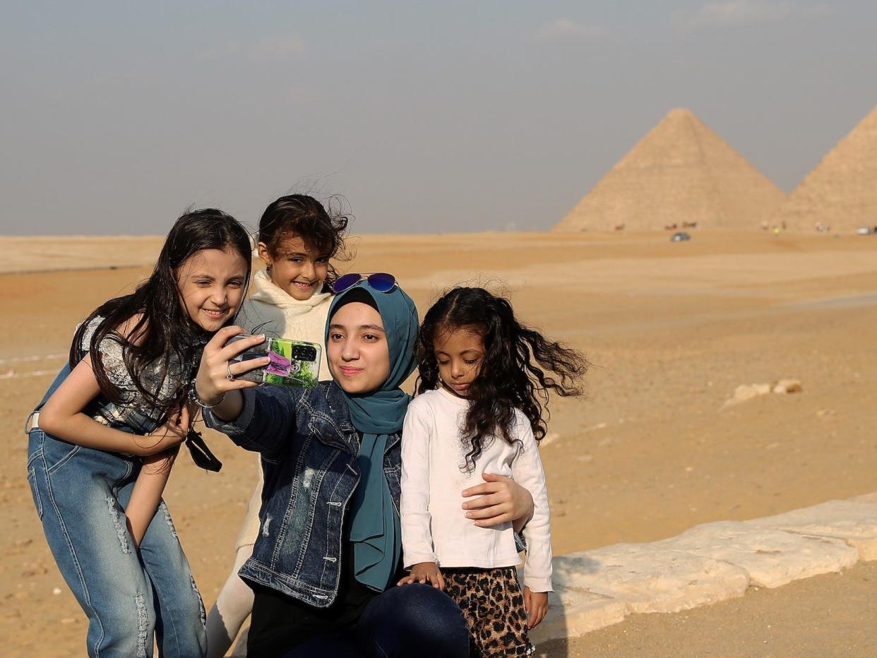 A family poses for a selfie in front of the pyramids of Giza in Egypt.