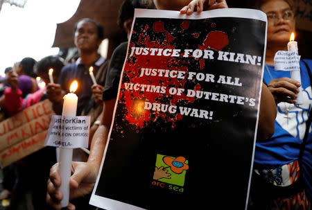 Protesters hold placards and lighted candles at the wake of Kian Loyd delos Santos, a 17-year-old high school student, who was among the people shot dead last week in an escalation of President Rodrigo Duterte's war on drugs in Caloocan city, Metro Manila, Philippines August 21, 2017. REUTERS/Erik De Castro