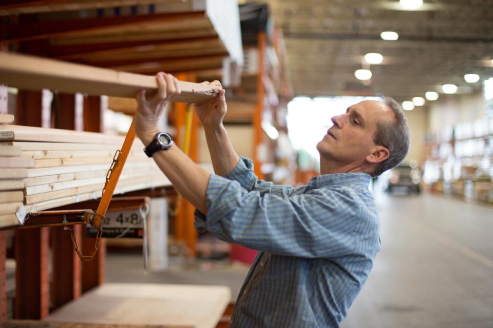 A person moving lumber off a shelf at a warehouse. 