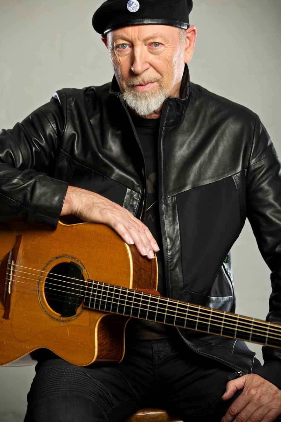 A portrait of Richard Thompson with a guitar on his knee.