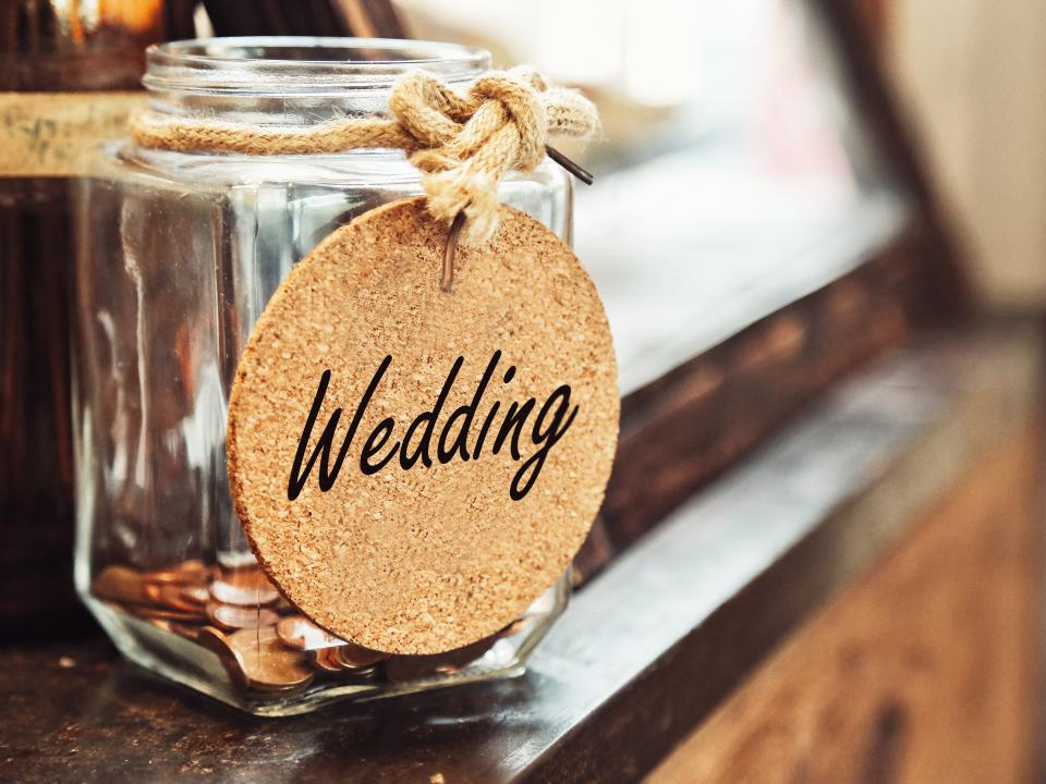 A jar with a "wedding" label on it and some coins inside it