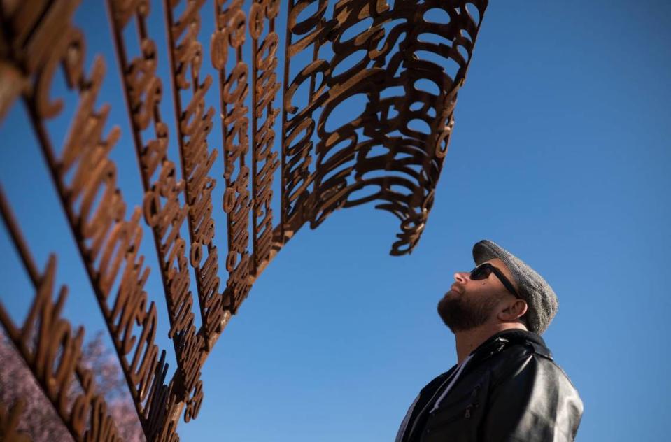 Andrew Bell, known as the the Sacramento Poet Laureate Andru Defeye, looks at a poem by Viola Weinberg, one of Sacramento’s first Poet Laureate, amid regional artist Troy Corliss’ “Poet’s Path, Circle of Laureates” art installation at South Natomas Community Park on March 15.