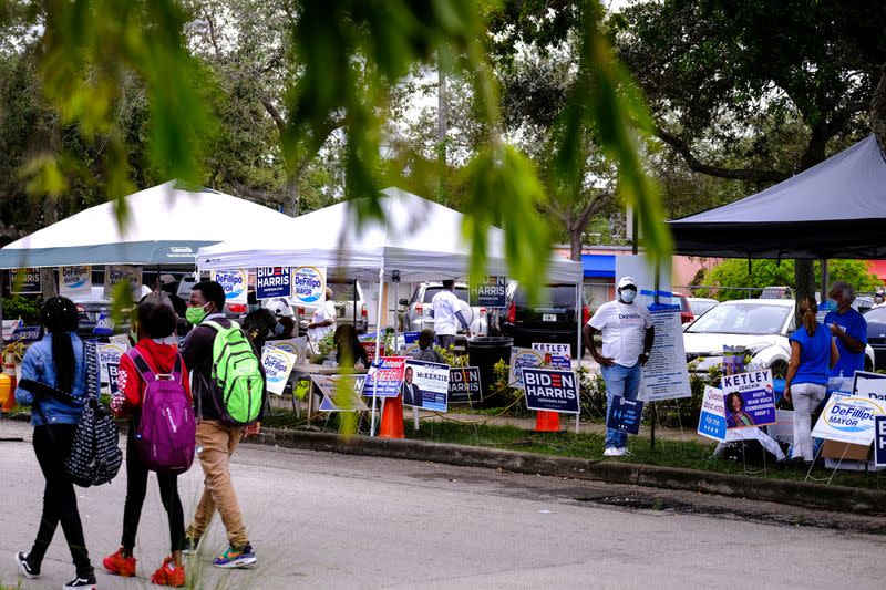 Gente hace campaña en la mesa de votación de la Biblioteca Pública de North Miami cuando comienza la votación anticipada antes de las elecciones en Miami, Florida, EEUU. 19 de octubre de 2020.