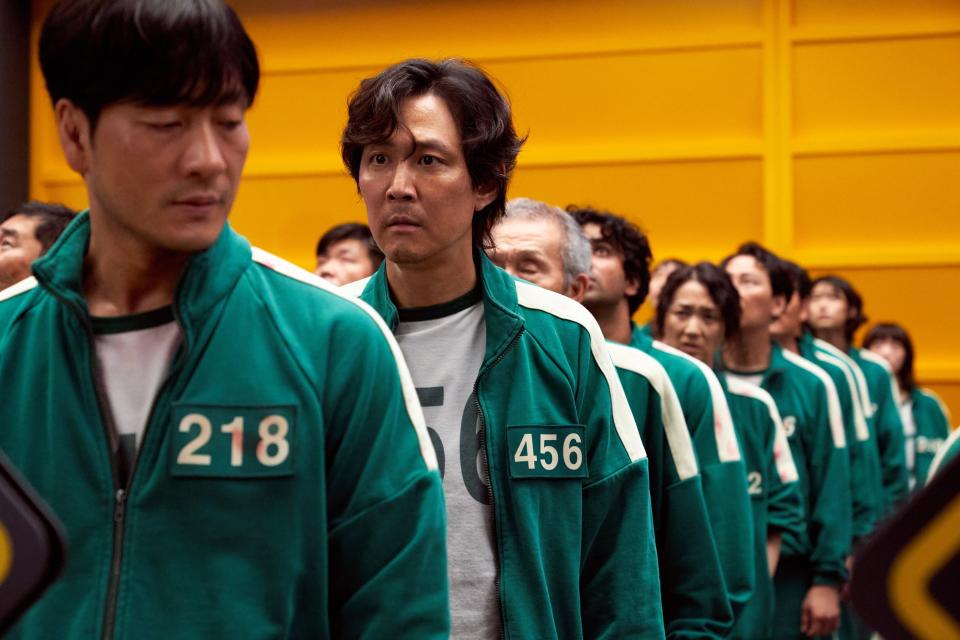 Gi-hun standing in a line of people all wearing the same uniform