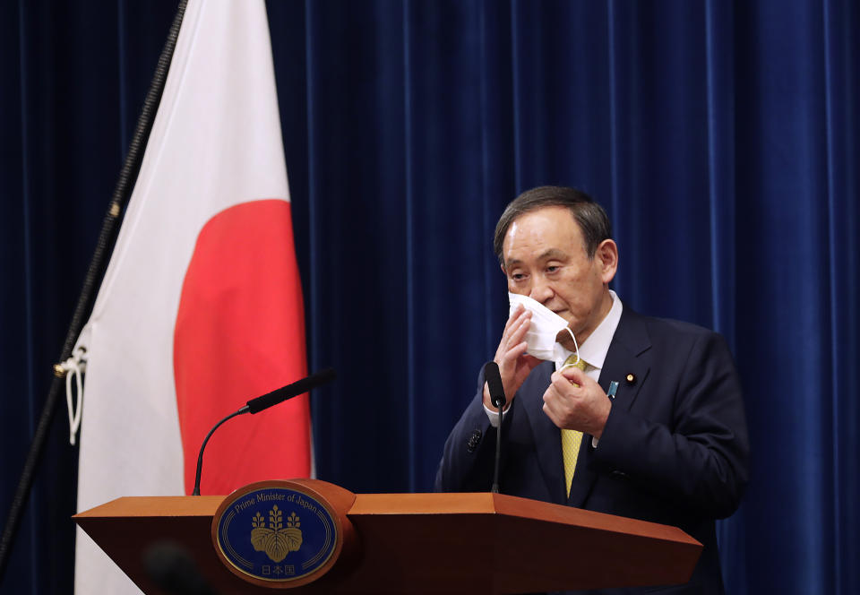 Japanese Prime Minister Yoshihide Suga removes his face mask during a news conference in Tokyo on Friday, Dec. 4, 2020. Suga announced a 2 trillion green fund to promote innovation and technology to achieve his pledge to achieve a carbon free society by 2050.(AP Photo/Hiro Komae, Pool)