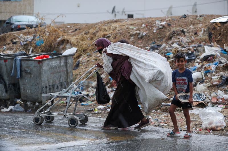 FILE PHOTO: Tunisian mother, Jamila Ghuwili, 55, pushes a trolley as she holds a bag of plastic on her back with her children around her in Tunis