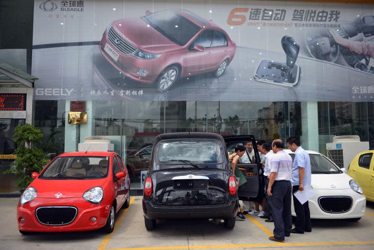 Customers look at cars at a Geely Auto dealership in Shanghai, on August 22, 2013