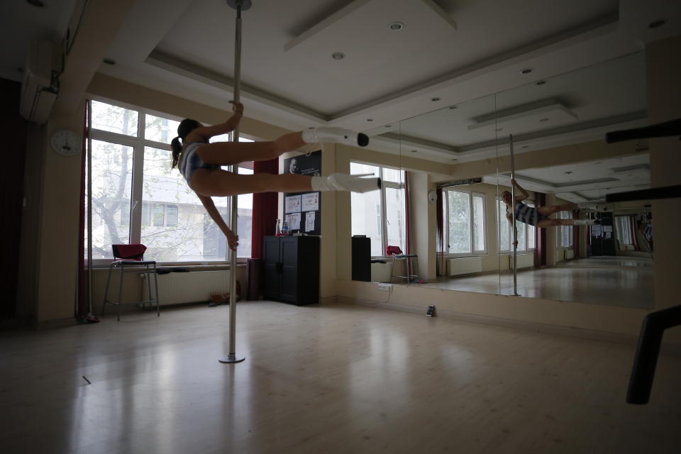 In this Thursday, April 30, 2020 photo, Tuba Parlak, 39, a pole dancing performer and instructor performs at her studio in Istanbul, during an online training session for students watching from home, due to the coronavirus restrictions. To stem the spread of COVID-19, Turkey closed down sports facilities in March but Parlak's students continued their pole lessons, using video conferencing. For students not having a pole at home, Parlak has designed a special programme to make sure they stay strong and fit. (AP Photo/Emrah Gurel)