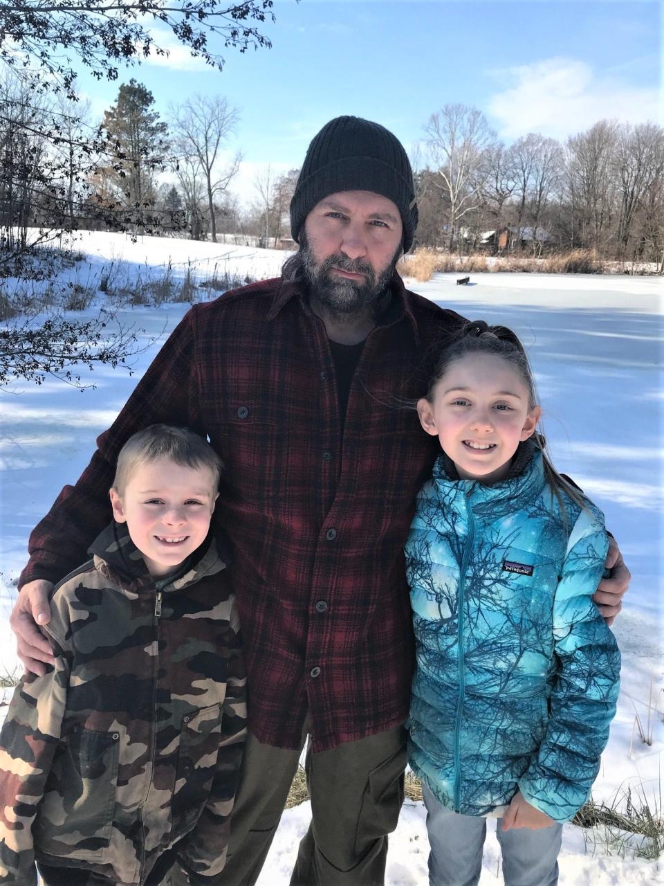 Kiala Dean, 11, (right) stands beside the pond on her family's 10-acre property with her brother, Kelson, 7, and father, Kevin.