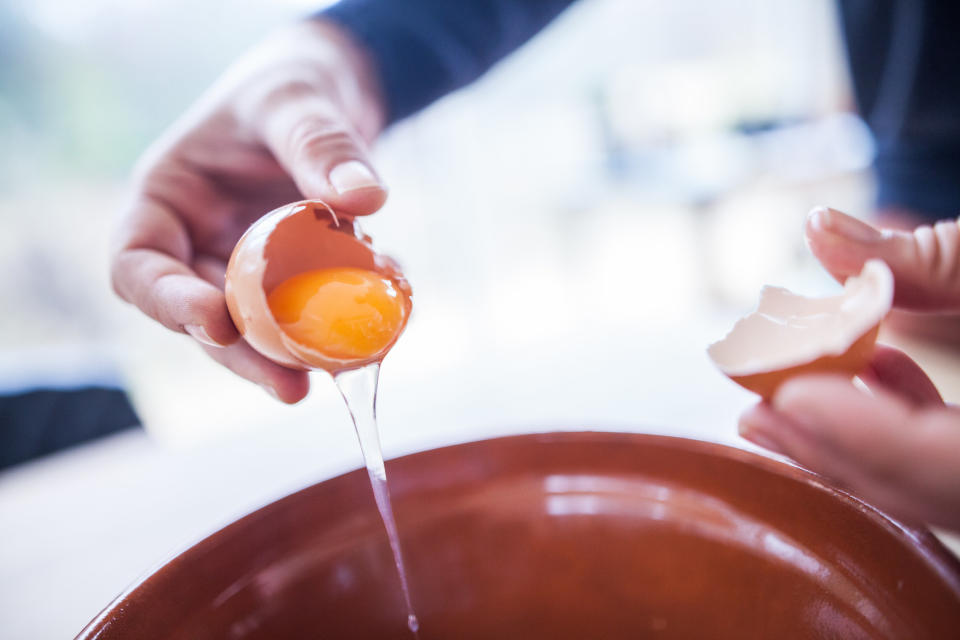 A person cracking an egg into a bowl