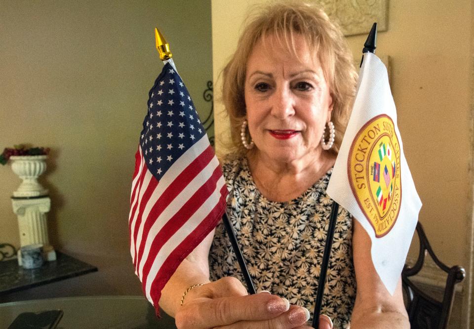 Diana Lowery holds up a U.S. flag and a Stockton Sister Cities Association flag. She has been the President of the Stockton Sister Cities Association and Chairperson of the Stockton Sister Cities Association Stockton, Ca./Parma, Italy Projects since 1998.