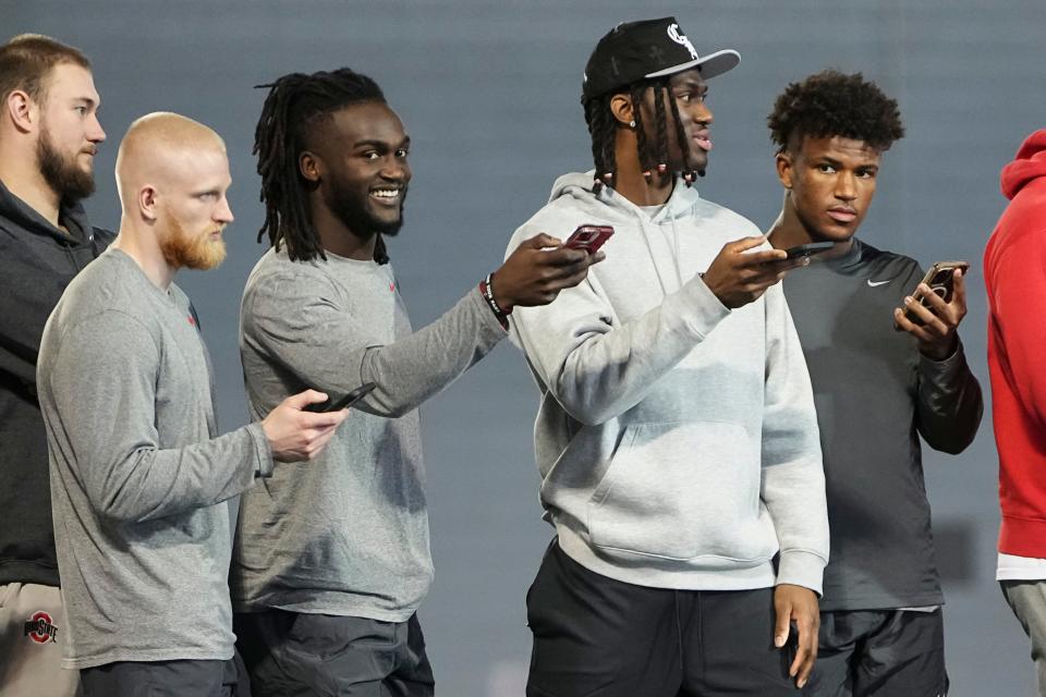 Mar 20, 2024; Columbus, Ohio, USA; From left, Ohio State Buckeyes wide receiver Reis Stocksdale, cornerback Denzel Burke, wide receiver Marvin Harrison Jr. and safety Caleb Downs use stopwatches on their phones to time players in the 40-yard dash during Pro Day at the Woody Hayes Athletic Center.