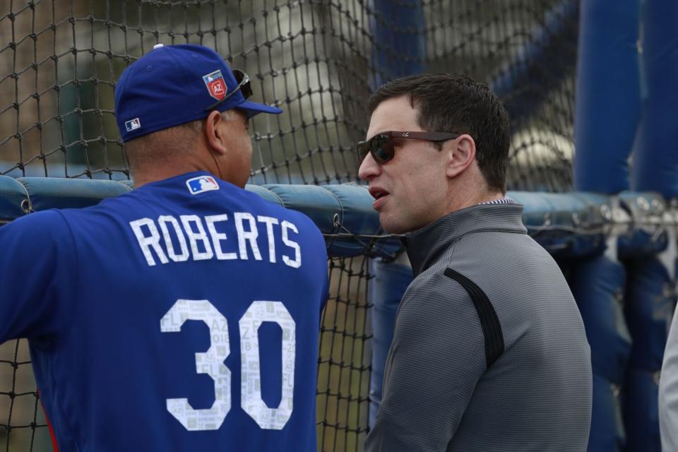 Andrew Friedman, presidente de operaciones de béisbol de los Dodgers, a la derecha, habla con el mánager de los Dodgers, Dave Roberts.