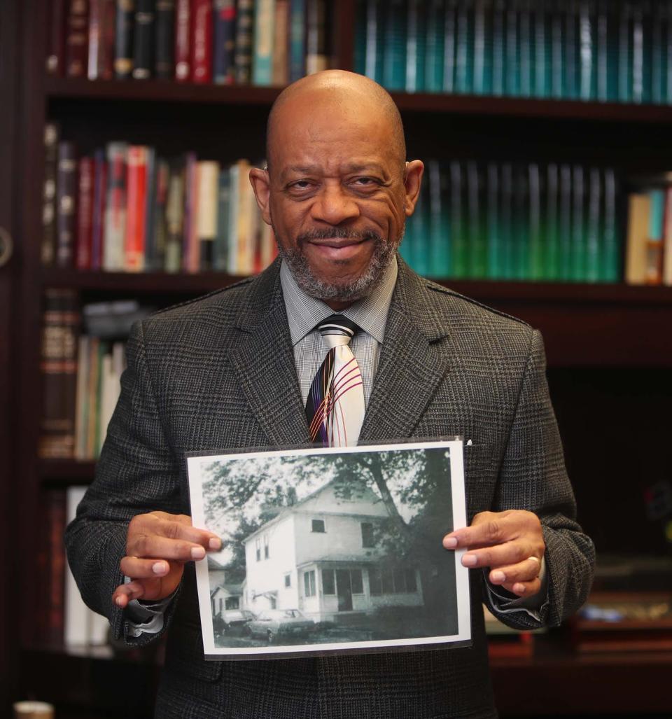 Bishop Joey Johnson, pastor of the House of the Lord, holds a photograph of his family's home on Douglas Street that his father purchased in the late 1950s. The family blames the Akron Innerbelt construction for the home's depreciation.