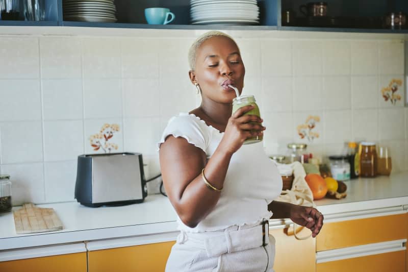 Young African woman enjoying a smoothie using a metal straw