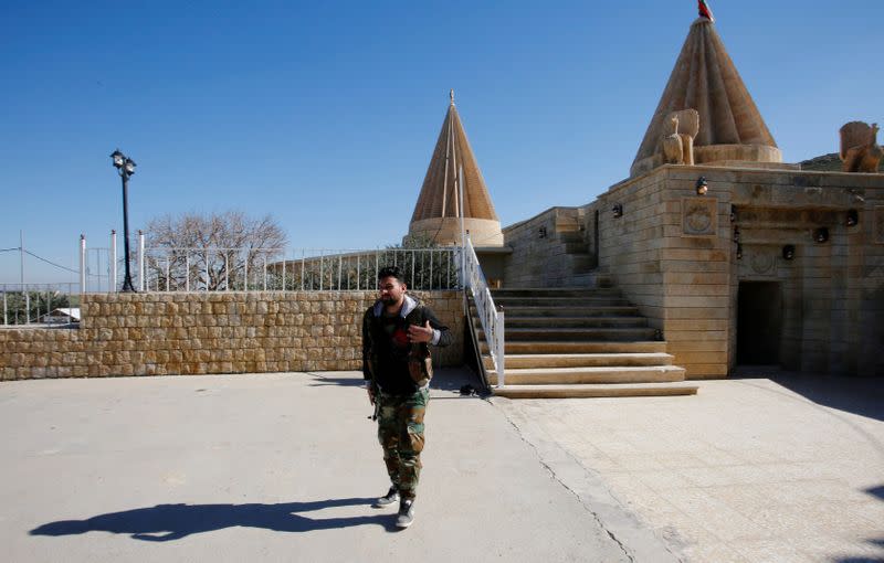 FILE PHOTO: A Yazidi fighter walks near Yazidi temple Sharaf al-Din, in Sinjar