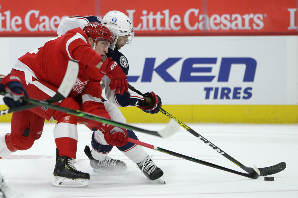 Detroit Red Wings defenseman Troy Stecher, left, battles Columbus Blue Jackets defenseman Seth Jones for the puck during the first period of an NHL hockey game Tuesday, Jan. 19, 2021, in Detroit. (AP Photo/Duane Burleson)