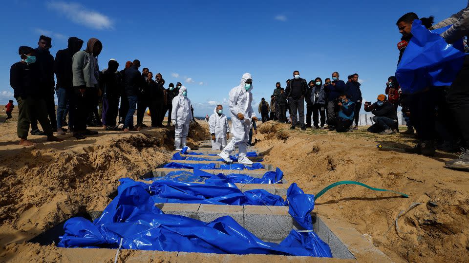 People bury Palestinians, including those killed in Israeli strikes and fire, at a mass grave in Rafah, January 30, 2024. - Mohammed Salem/Reuters