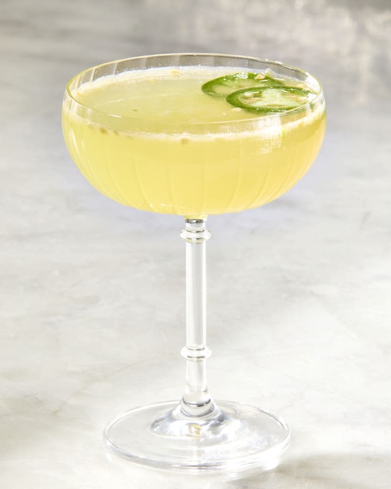 Photo of a single bee sting cocktail with sliced jalapeno pepper garnish.