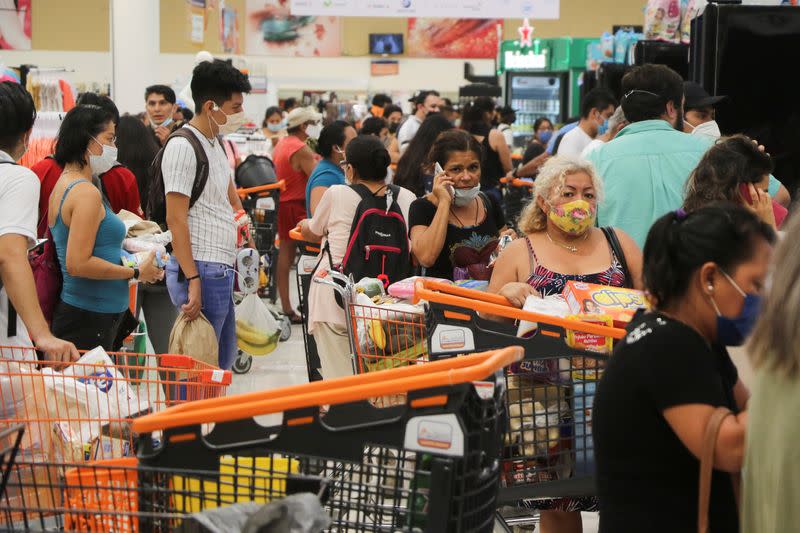 People queue to pay for goods at a supermarket, in preparation for the arrival of Hurricane Delta, in Cancun