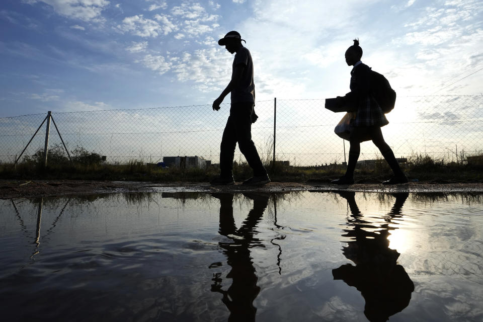 File — A man and woman walks over puddled water along a street from an overflowing reservoir in Hammanskraal, Pretoria, South Africa, Friday, May 26, 2023. Today the ruling African National Congress (ANC) faces growing dissatisfaction from many who feel it has failed to live up to its promises. (AP Photo/Themba Hadebe/File)