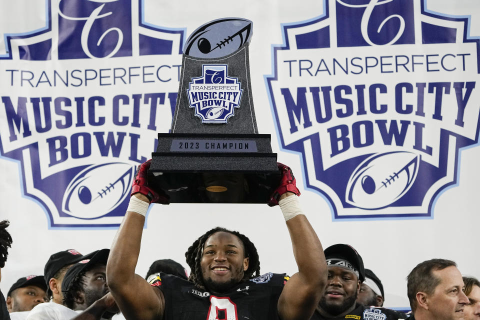 Maryland defensive lineman Jordan Phillips (8) hoists the trophy after the team's 31-13 win against Auburn in the Music City Bowl NCAA college football game Saturday, Dec. 30, 2023, in Nashville, Tenn. (AP Photo/George Walker IV)