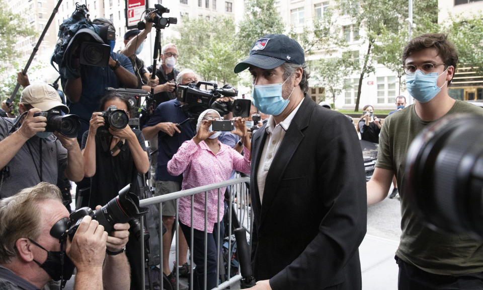 Michael Cohen, center, President Donald Trump's former personal attorney, returns to his apartment after being released from prison, Friday, July 24, 2020, in New York. District Judge Alvin Hellerstein ordered Cohen released on parole saying he believes the government retaliated against him for writing a book about Trump. (AP Photo/Mark Lennihan)