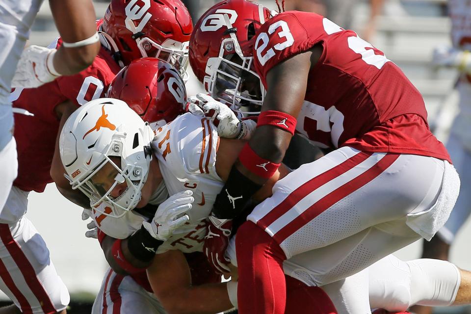 OU's DaShaun White (23) and Delarrin Turner-Yell (32) bring down Texas quarterback Sam Ehlinger (11) during the Sooners' 53-45 win in Dallas on Oct. 10, 2020.
