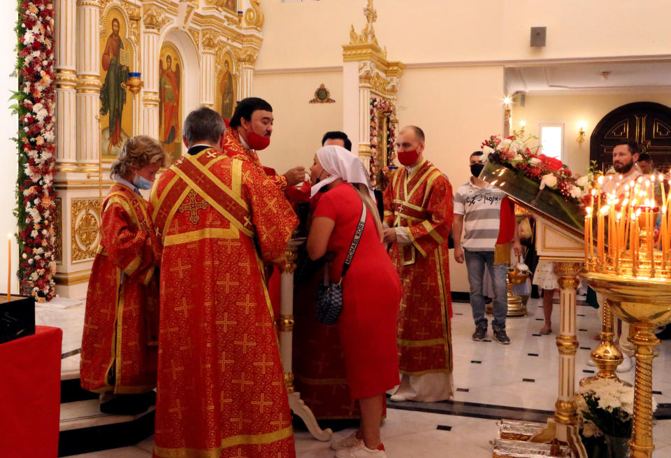 A Russian-speaking churchgoer receives communion at the Christian Orthodox Church in Sharjah, United Arab Emirates, Sunday, April 24, 2022. Hundreds of Russians and Ukrainians alike crowded into the only Russian Orthodox Church on the Arabian Peninsula on Sunday to celebrate the most important Christian religious festival of the year — far from home and in the shadow of a war that has brought devastation to Ukraine and international isolation to Moscow. (AP Photo/Isabel Debre)
