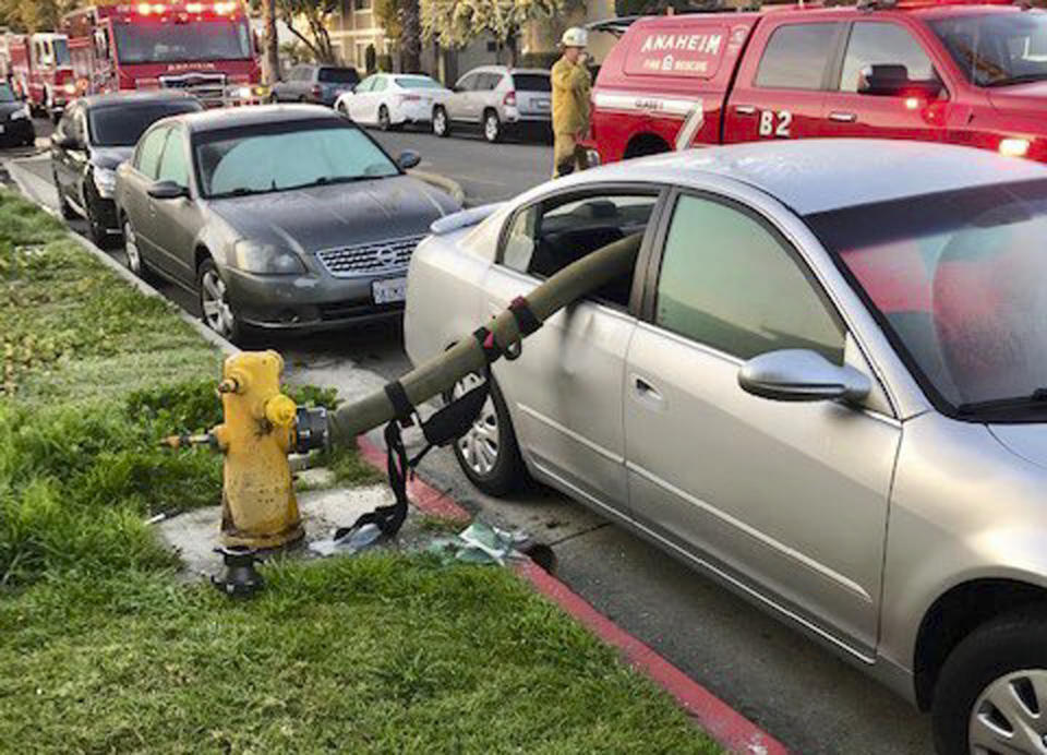 This Feb. 26, 2019 photo provided by the Anaheim Fire Department and Anaheim Police Department shows a car with a firehose running through the rear side windows in Anaheim, Calif. A California fire department enflamed some social media users but delighted others by posting pictures of the busted-out windows of a car that parked in front of a fire hydrant. In a Twitter thread posted Wednesday, the Anaheim Fire Department asked the public: "Ever wonder what happens when a car is parked in front of a fire hydrant and a fire breaks out." (Anaheim Fire Department and Anaheim Police Department via AP)