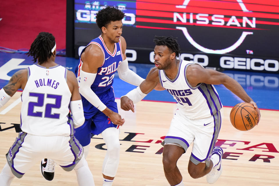 Sacramento Kings' Buddy Hield, right, dribbles past Philadelphia 76ers' Matisse Thybulle, center, during the second half of an NBA basketball game, Saturday, March 20, 2021, in Philadelphia. (AP Photo/Matt Slocum)