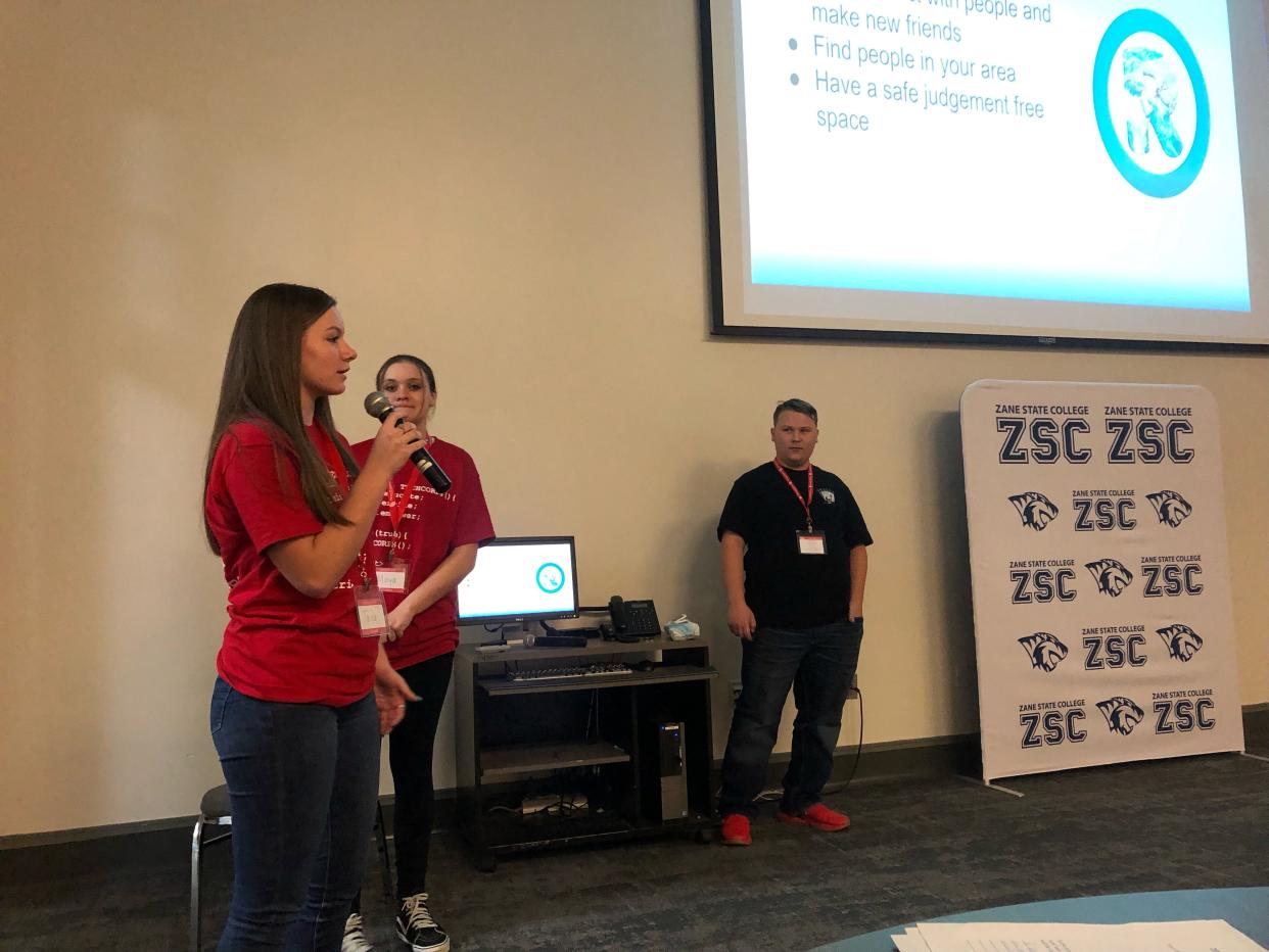 Maya Sensabaugh (center) watches as her sister, Taya, gives the presentation of their app during the TECH CORPS Hackathon at Zane State College.