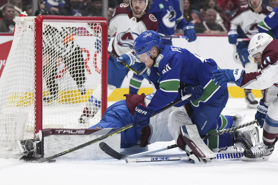 Vancouver Canucks' Elias Pettersson, front, of Sweden, is stopped by Colorado Avalanche goalie Alexandar Georgiev, of Russia, during the first period of an NHL hockey game in Vancouver, British Columbia on Thursday, Jan. 5, 2023. (Darryl Dyck/The Canadian Press via AP)