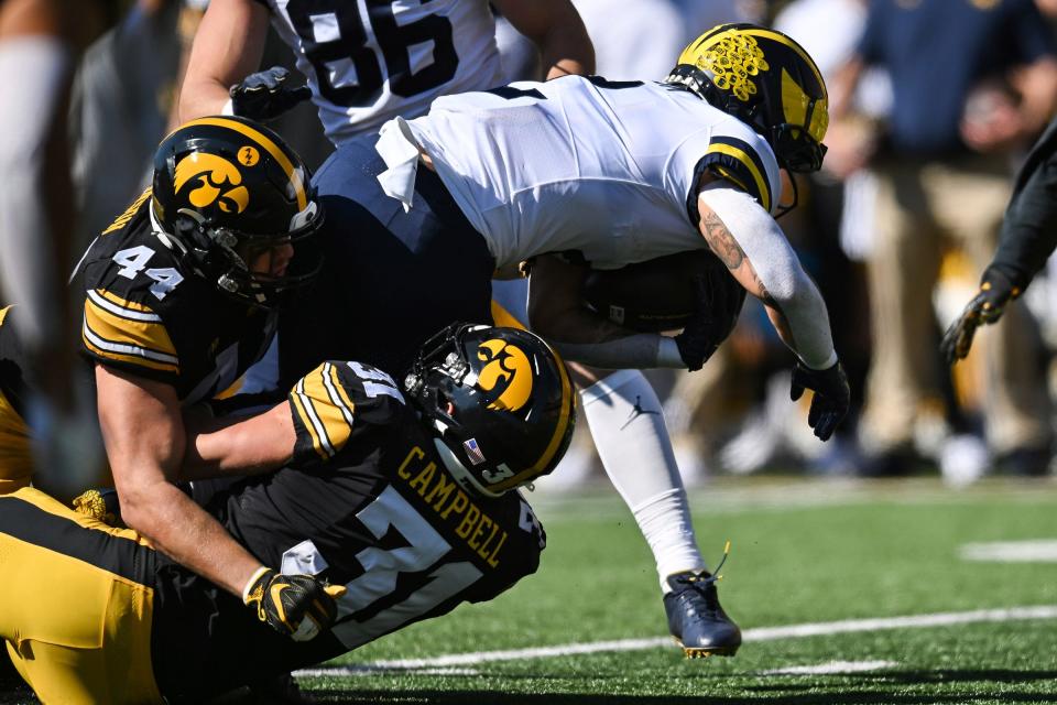 Michigan running back Blake Corum runs the ball as Iowa linebacker Seth Benson, left, and linebacker Jack Campbell make the tackle during the first quarter on Saturday, Oct. 1, 2022, in Iowa City.