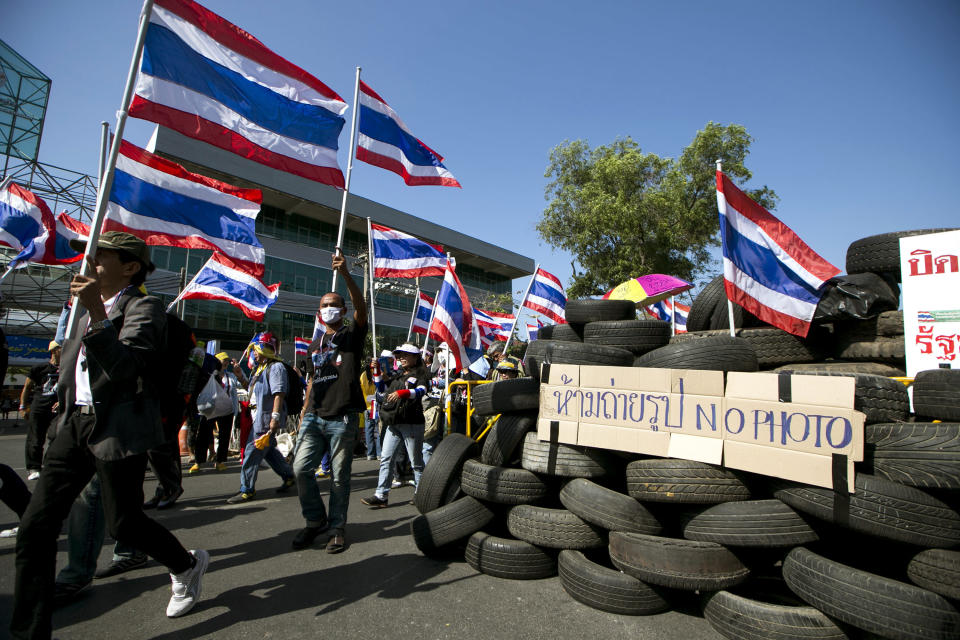 Thai anti-government protesters march with national flags while heading to shut down the office of the National Economic and Social Development Board Tuesday, Jan. 14, 2014 in Bangkok, Thailand. Anti-government protesters who blocked off intersections across Thailand's capital began marching toward several government ministries Tuesday on the second day of a renewed push to derail elections next month and unseat the prime minister. (AP Photo/Wason Wanichakorn)