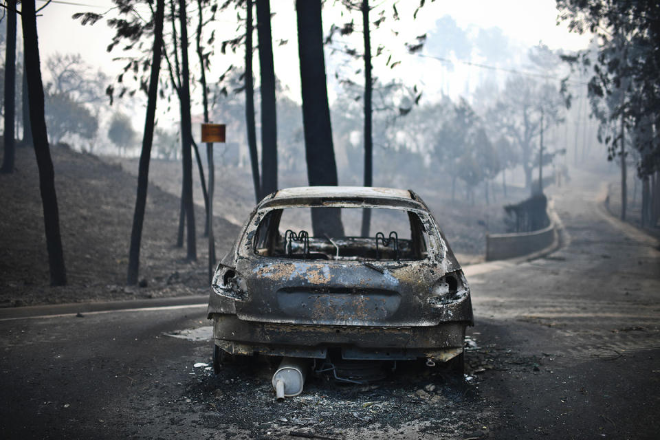 <p>A burned out car is shown on a road after a wildfire in Pedrogao, in central Portugal, June 18, 2017. (Patricia De Melo Moreira/AFP/Getty Images) </p>