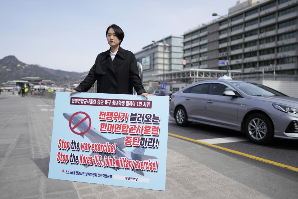 A woman holds a banner demanding stop the joint military drill between South Korea and the United States, during a protest across the U.S. Embassy in Seoul, South Korea, Friday, March 17, 2023. North Korea said Friday it fired an intercontinental ballistic missile to "strike fear into the enemies" as South Korea and Japan agreed at a summit to work closely on regional security with the United States and staged military exercises around the region. (AP Photo/Lee Jin-man)