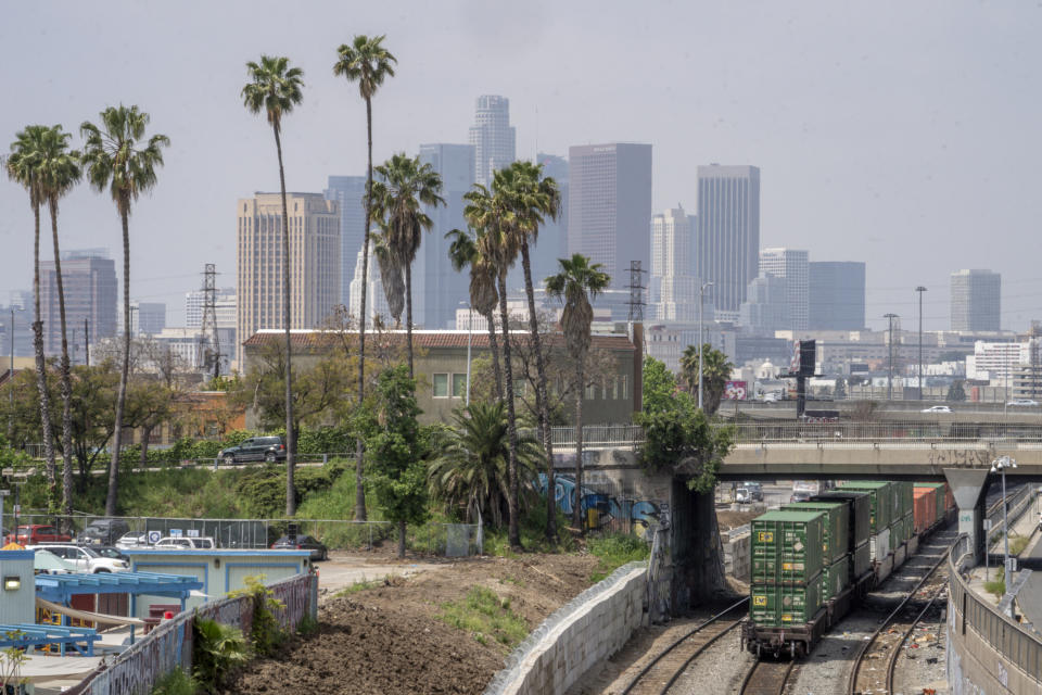 Los Angeles skyline is seen above a train rolling near the Union Pacific LATC Intermodal Terminal on Tuesday, April 25, 2023, in Los Angeles. California's Air Resources Board is set to vote on a rule to cut greenhouse gas and smog-forming emissions from diesel-powered locomotives used to pull rail cars through ports and railyards. (AP Photo/Damian Dovarganes)