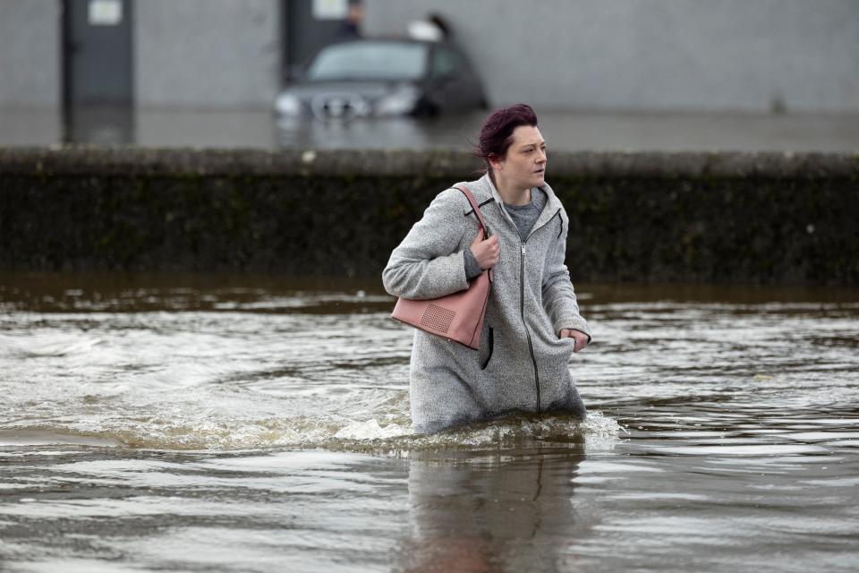 A woman tries to walk through water as it flows through the streets after heavy rain caused extensive flooding in Ireland (REUTERS)