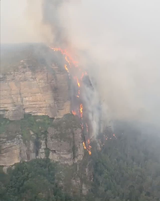 A fire burns at the side of a cliff in Blue Mountains