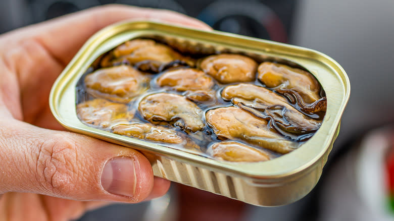 Person holding can of oysters