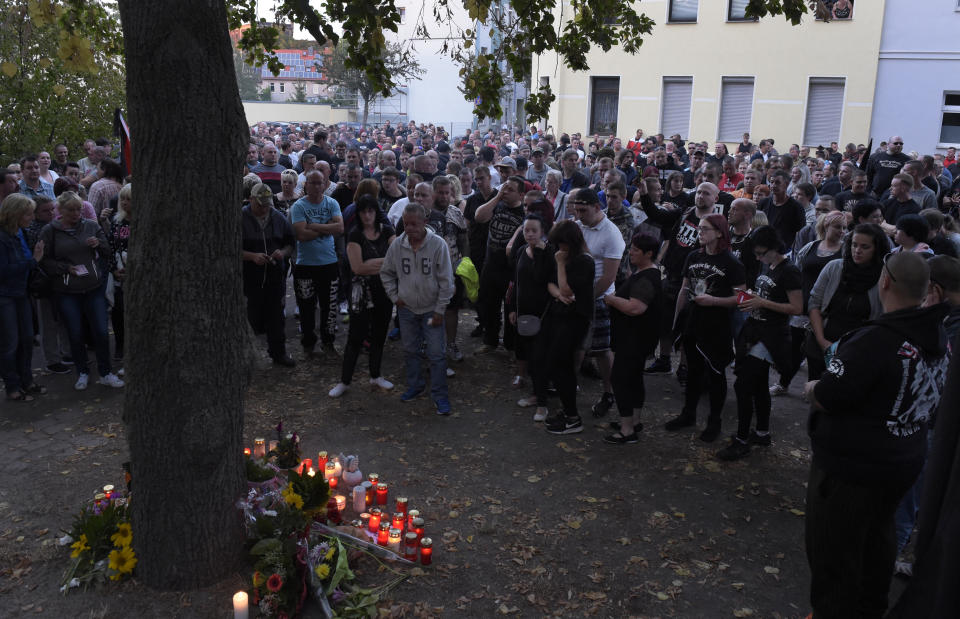 People gather at the site of a deadly brawl in Koethen, 90 miles southwest of the German capital Berlin, Sunday, Sept. 9, 2018, after police has arrested two Afghan men on suspicion of killing a 22-year-old German man. (AP Photo/Jens Meyer)