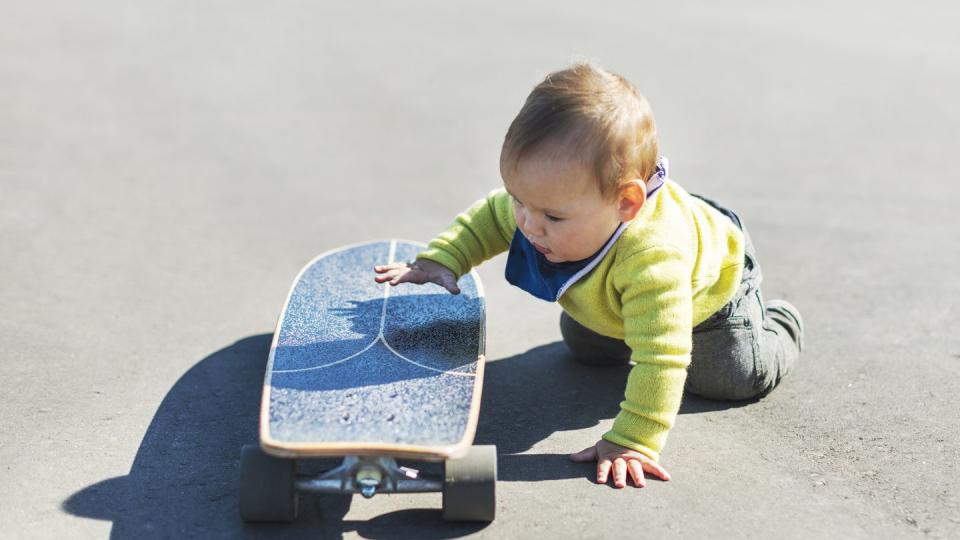 little baby boy playing with big skateboard in park