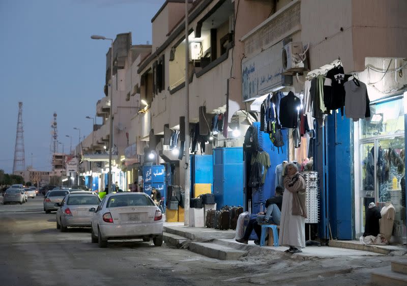 A man stands in front of a clothing store in the city of Sirte